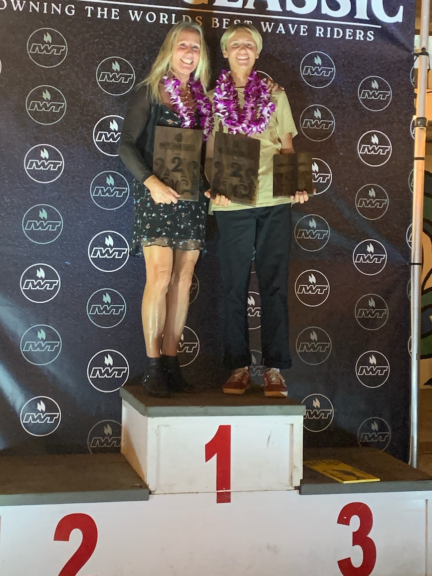 A woman and a young man stand on a podium, smiling