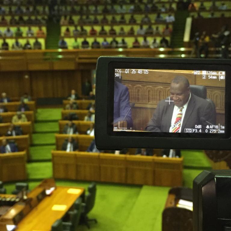 James Marape in the screen of a camera sitting in PNG's parliament.