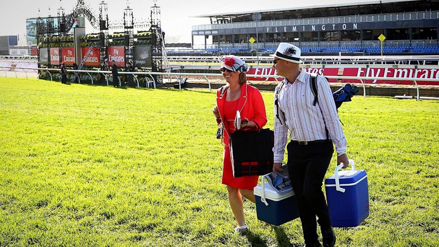 Racegoers arrive early and walk across the racetrack at Flemington racecourse on Melbourne Cup day.
