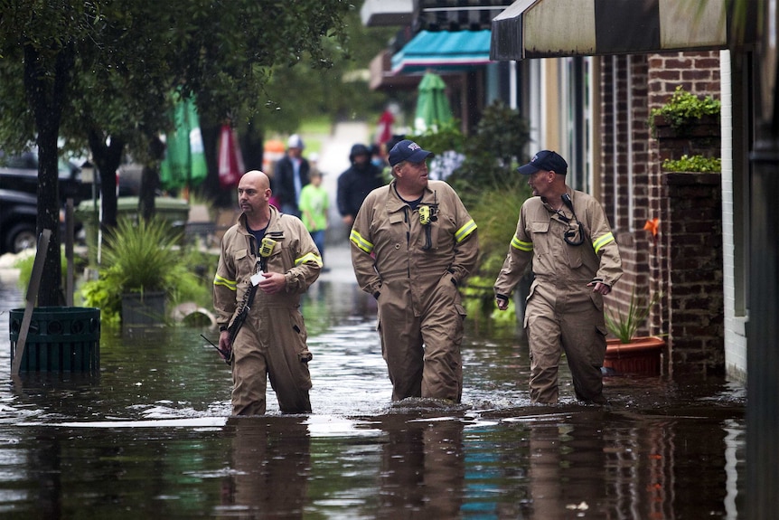 Members of the Georgetown fire department wade through a flooded street in Georgetown, South Carolina