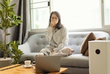Woman on couch holding her nose looking at an air purifier