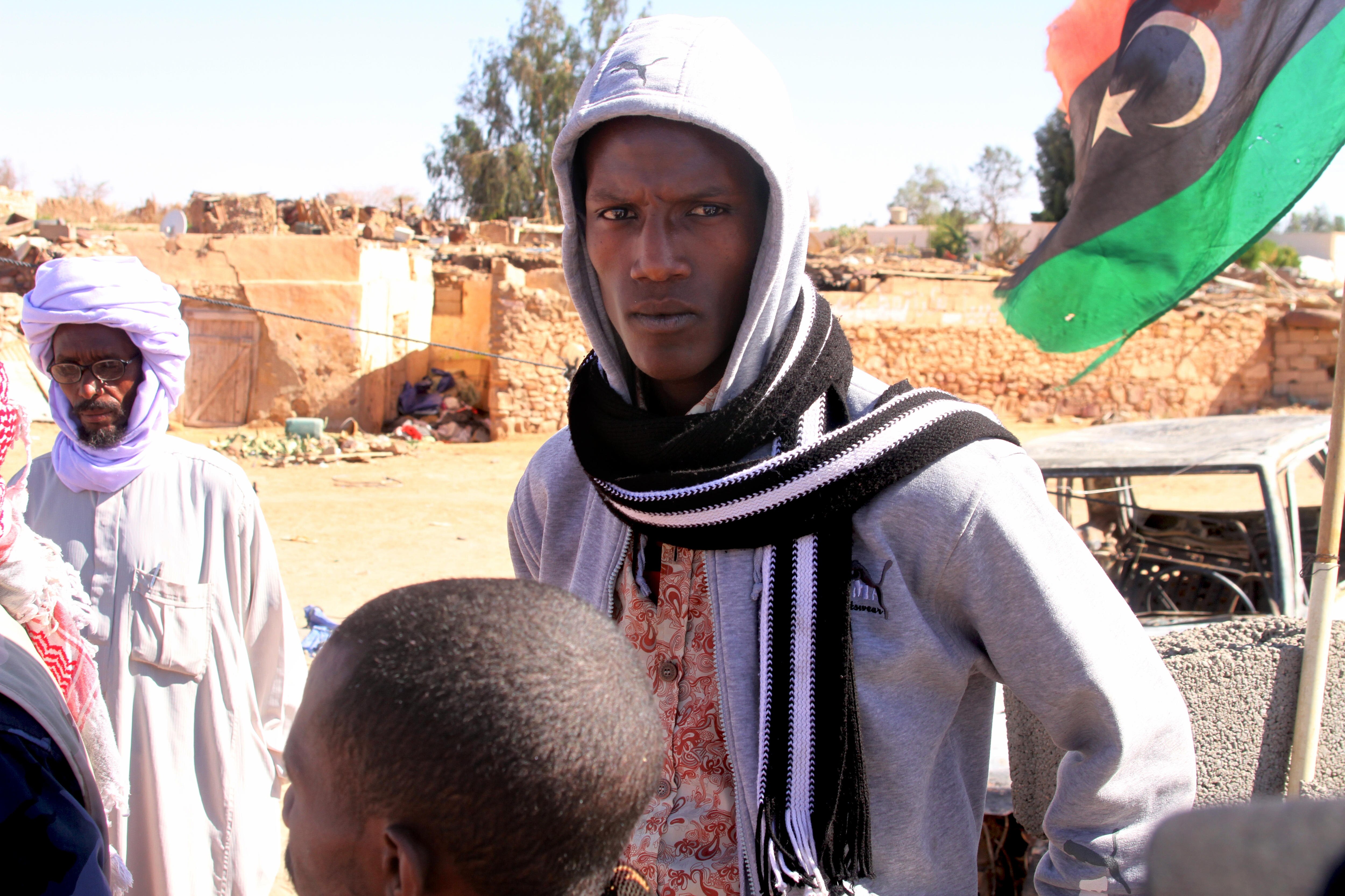 A man stands next to a Libyan flag.