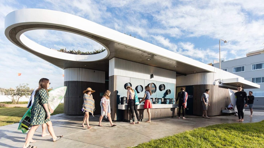 A fancy toilet block with surfers walking in and out