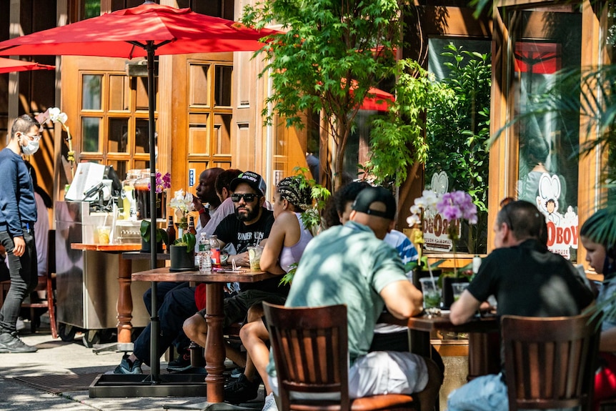 People eat in outdoor seating outside a restaurant in New York.