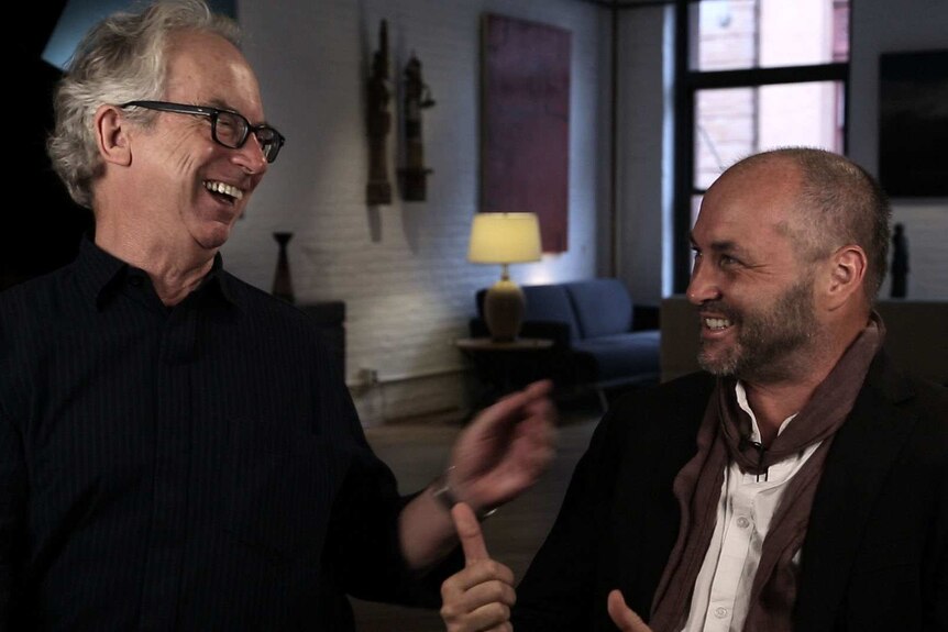 Authors Peter Carey and Colum McCann look at each other while laughing.