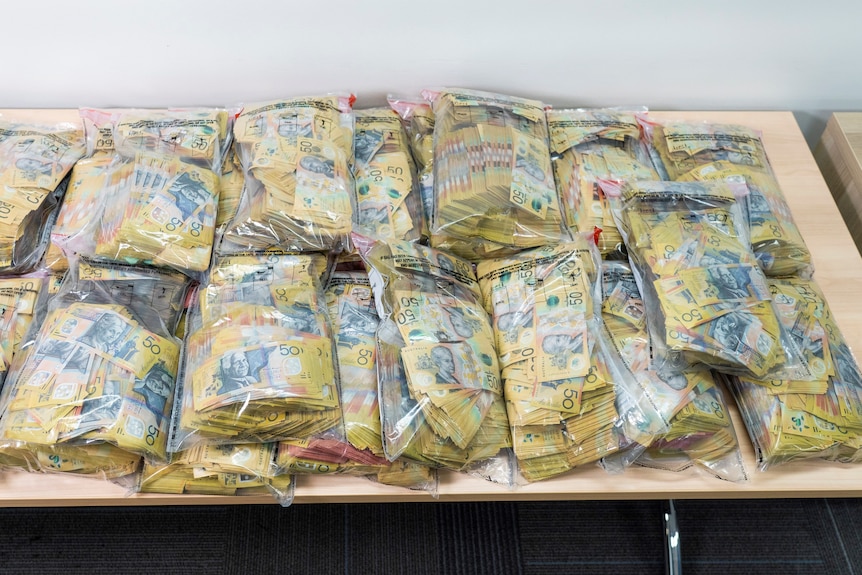 piles of 50 dollar notes in plastic bags displayed on a table 