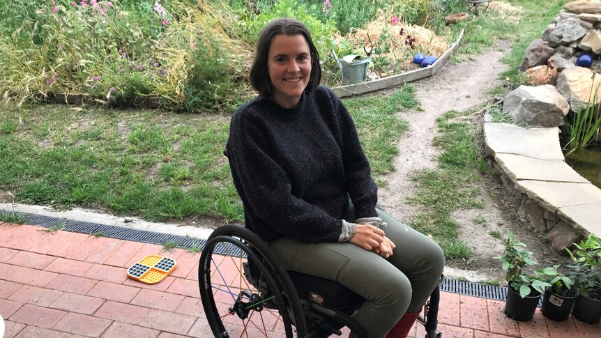 Rubie Gallagher sitting on her porch with a wild garden behind her.