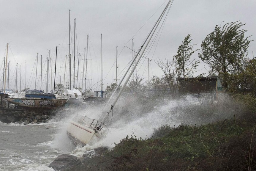 A sailboat smashes onto rocks after breaking free from its mooring on City Island in New York.