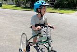 A young boy rides down a street on a frame runner
