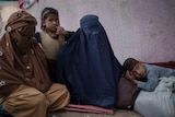Women dressed in burkas sit with their children at a camp for internally displaced.