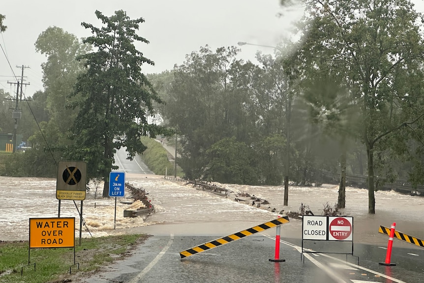 Road Closed signs in front of a flooded road 