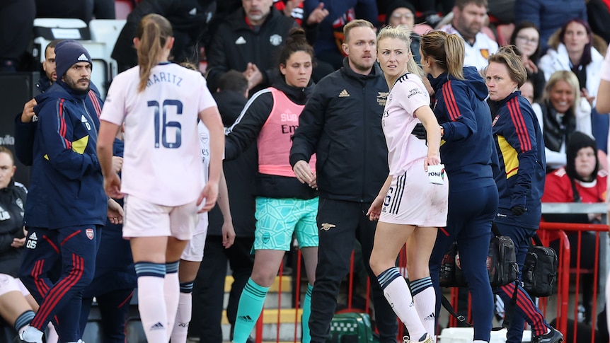 Leah Williamson turns to hand over her captain's armband as she is led from the field with an injury during an Arsenal match.