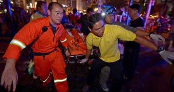 Thai rescue workers carry an injured person after a bomb exploded in central Bangkok