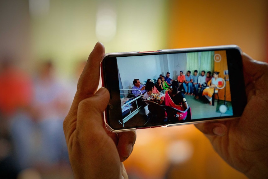 An image of a phone filming a group of people opposed to virginity testing hold a meeting.