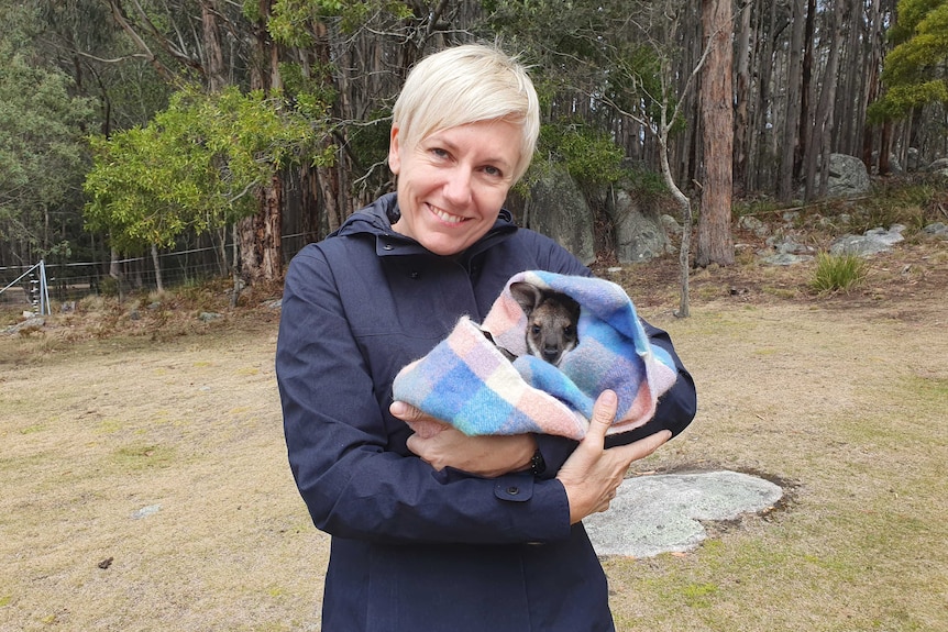 Woman holding a joey in a blanket.