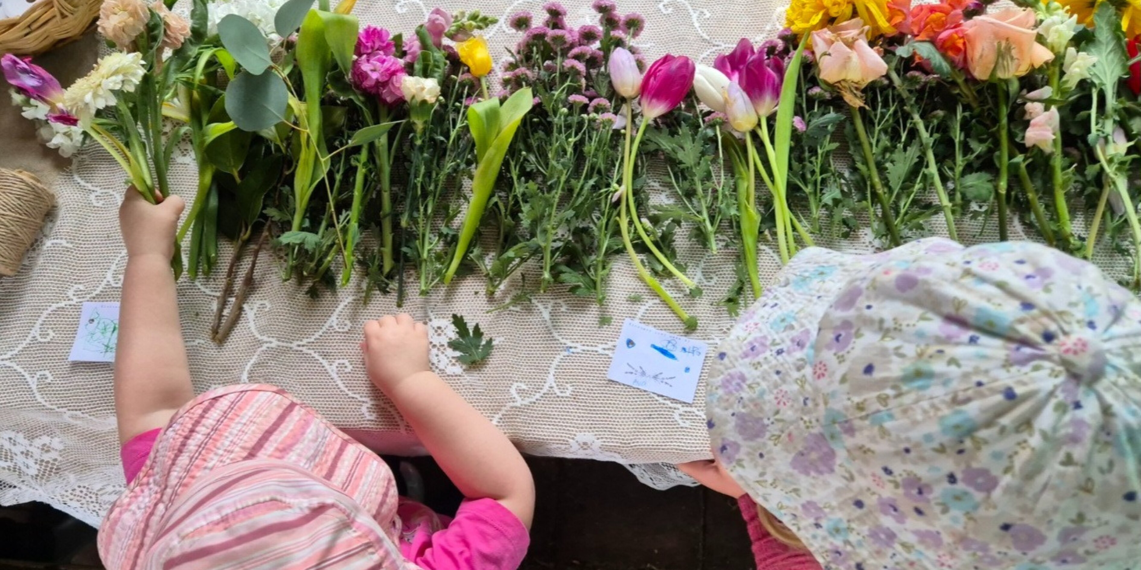 a top view showing young children's hands arranging flowers from tabletop craft activity.  