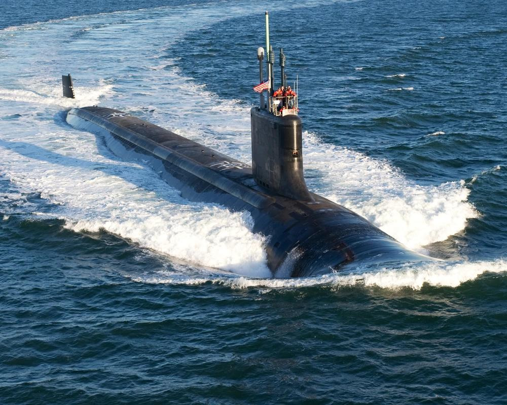 一艘潜艇在水中移动，在它身后造成巨大的尾流，一些船员在甲板上方可见。