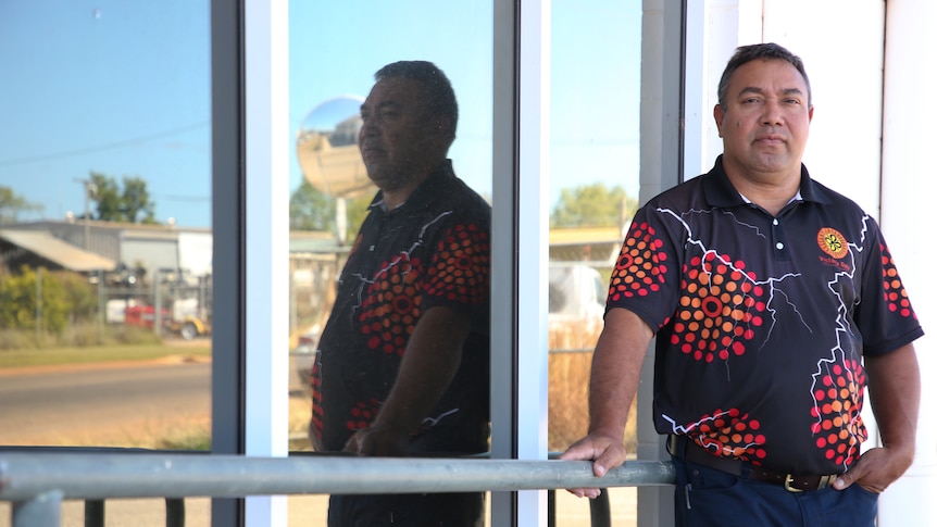 Indigenous mayor Brian Pedwell leans against a glass building looking concerned.