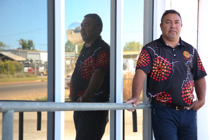 Indigenous mayor Brian Pedwell leans against a glass building looking concerned.