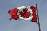 The red and white Canadian flag is seen with a maple leaf in the centre. The sky above it is blue.