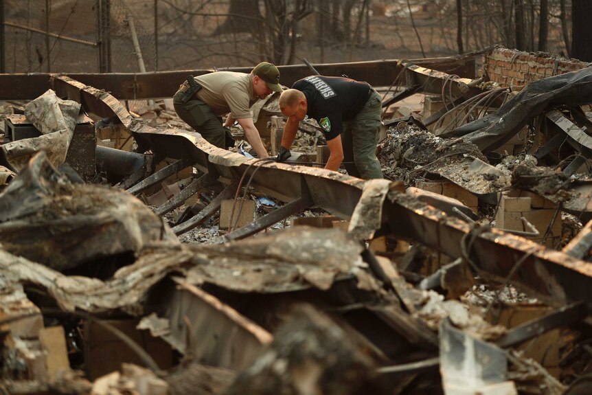 Officials prepare to move human remains found at a burned out home from the Camp Fire in California.