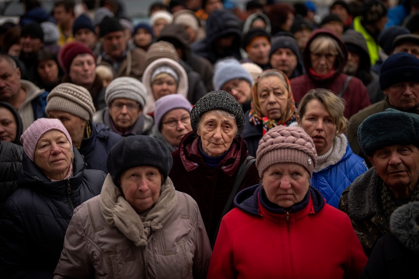 Crowds of people wait for food.