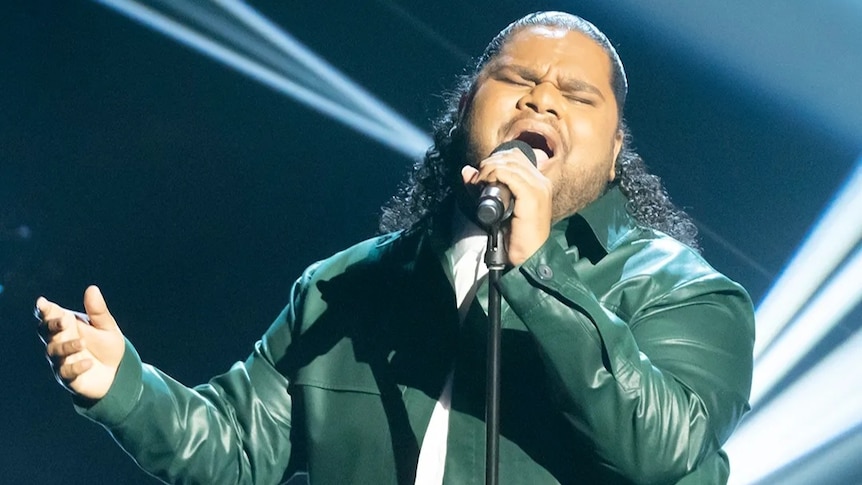 A man in a leather jacket singing into a microphone.