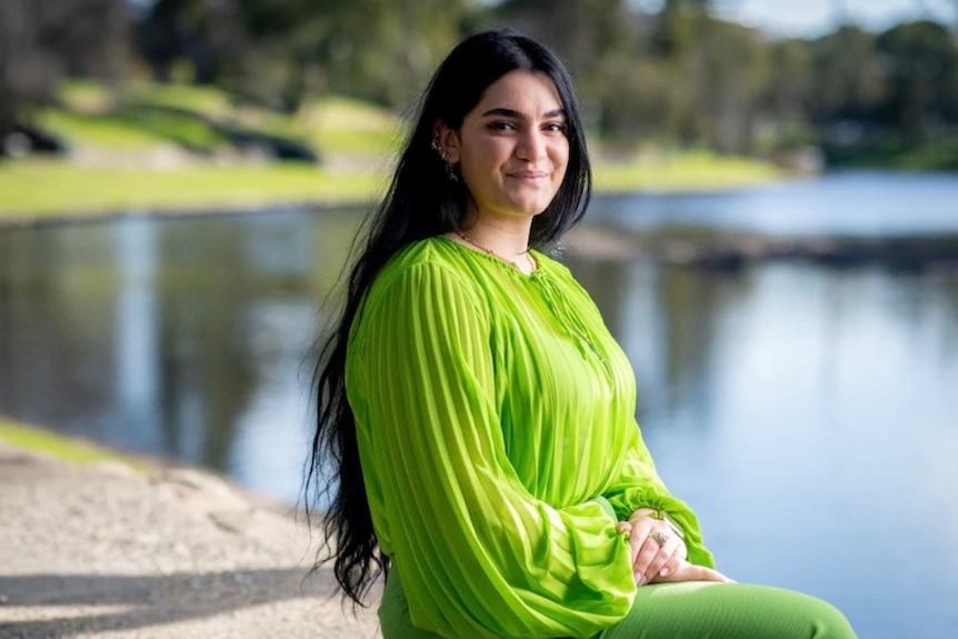 Yeganeh Soltanpour sits outside near a body of water. 