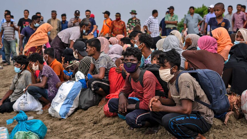 Ethnic-Rohingya people rest after arriving by boat on a beach in North Aceh.