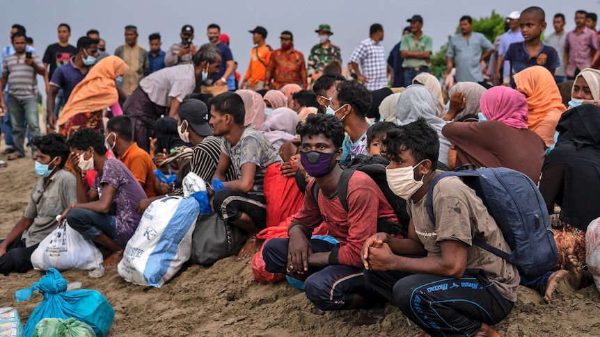 Ethnic-Rohingya people rest after arriving by boat on a beach in North Aceh.