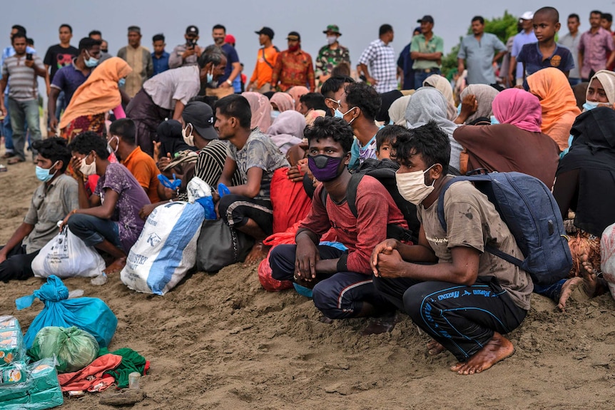 Ethnic-Rohingya people rest after arriving by boat on a beach in North Aceh.