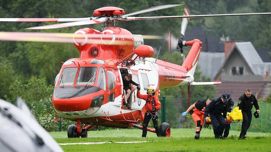 emergency crews take an injured person on a stretcher from a helicopter