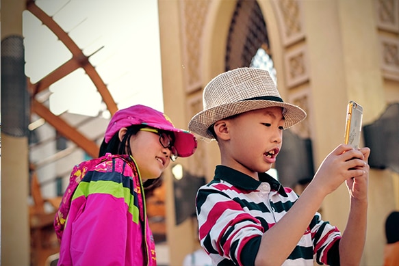 Two  kids at a theme park looking at a smartphone