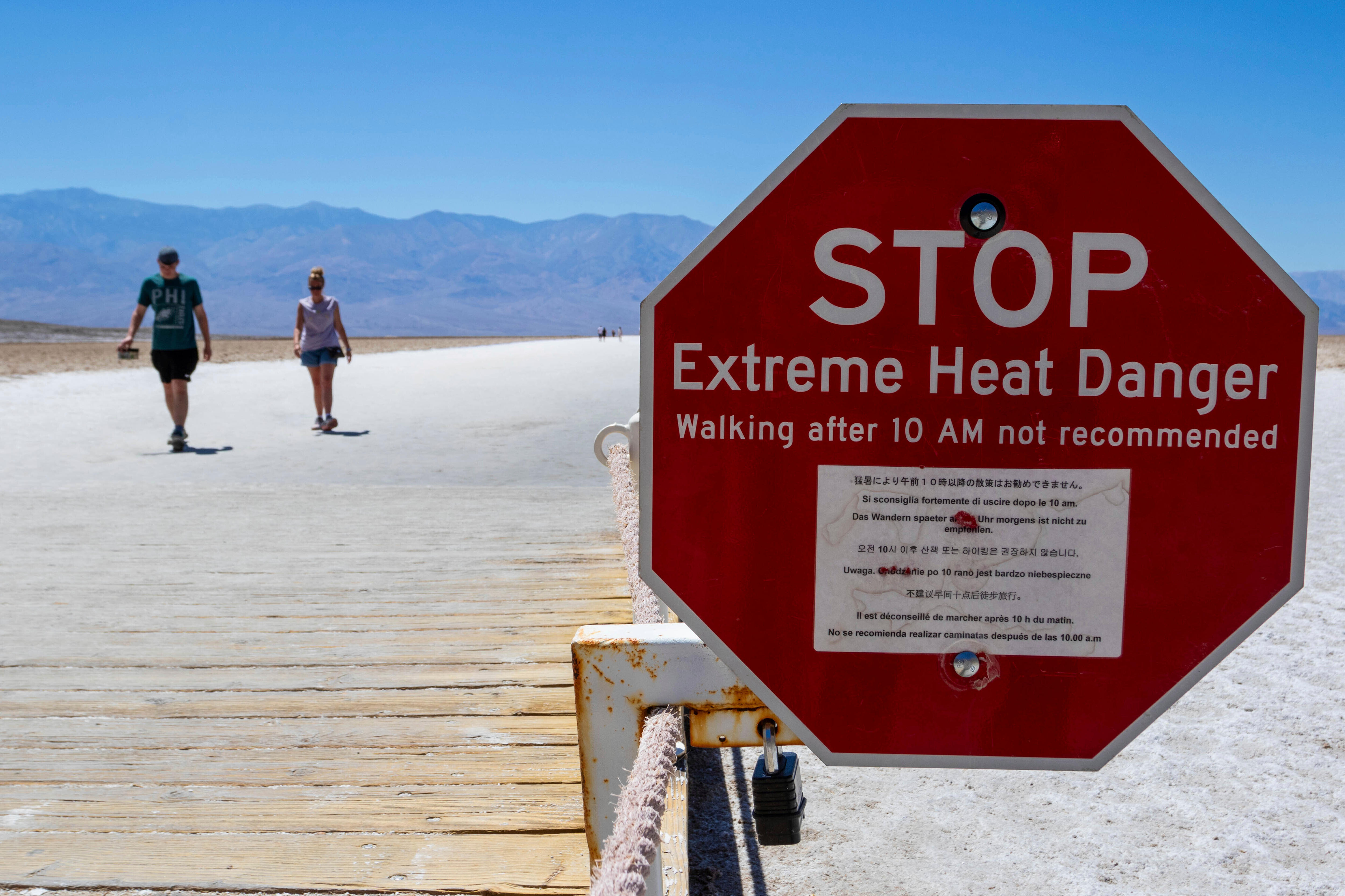 A red sign warns people of extreme heat in multiple languages.