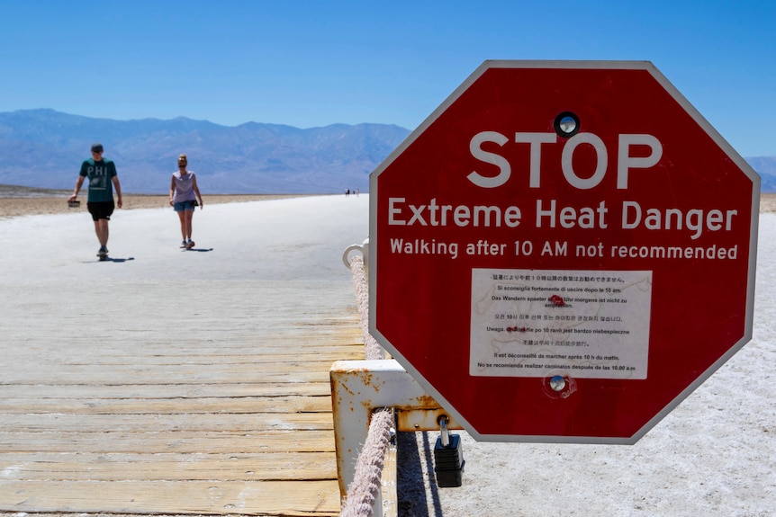 A red sign warns people of extreme heat in multiple languages.