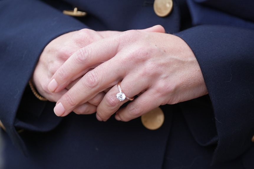 A close shot of Haydon's engagement ring on her folded hands.