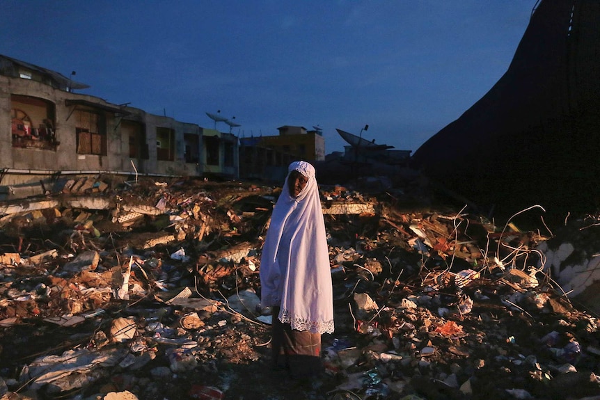 Woman stands in market ruins