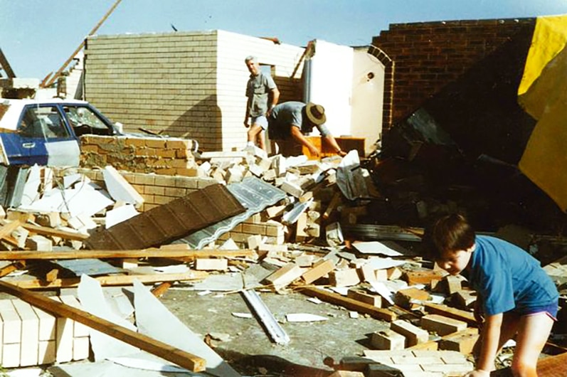 People combing through broken brickwork in the shattered remains of a house