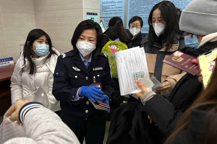 Policewoman collects passports from people at community police station.