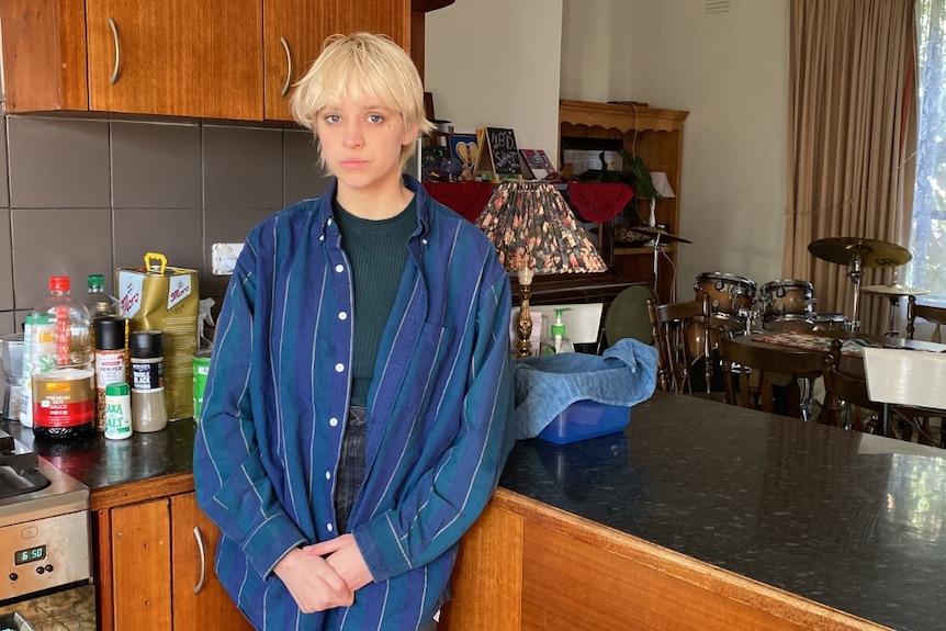A young white woman with short blonde hair standing in a kitchen.