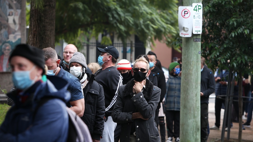 People in face masks queue up