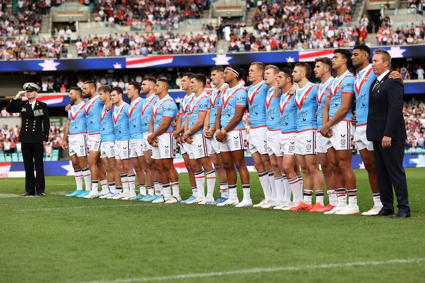 Sydney Roosters NRL players stand in line for the national anthems during Anzac Day at the SCG.