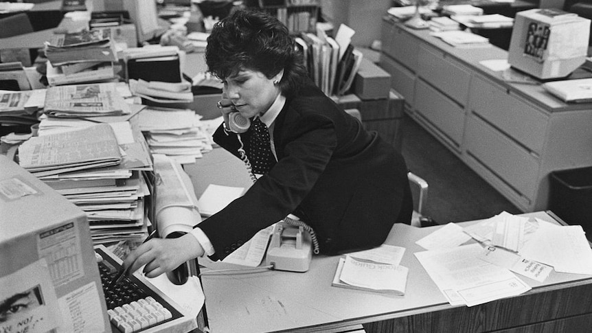 woman at a messy desk in the 1980s