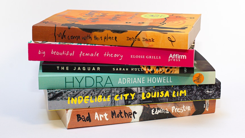 A stack of six books, carefully arranged. They are of different widths and colours, including pink and turquoise.