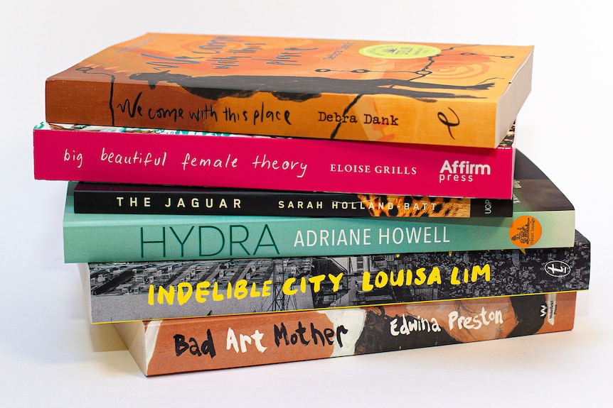 A stack of six books, carefully arranged. They are of different widths and colours, including pink and turquoise.