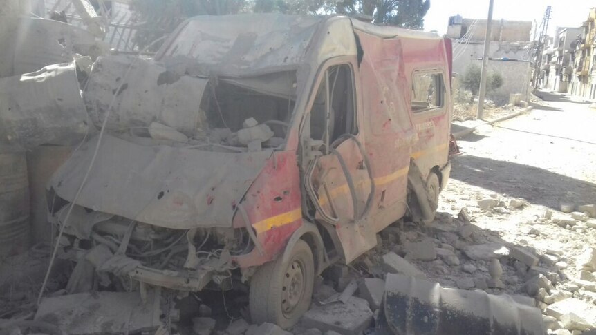 A red van crushed with debris and covered in dust