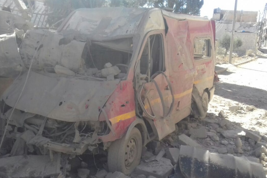 A red van crushed with debris and covered in dust