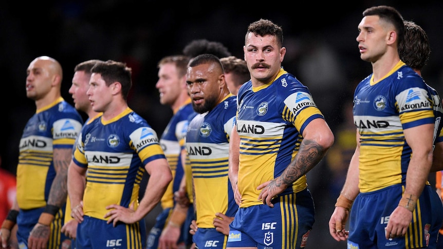 Parramatta Eels players stand in a line and look disappointed
