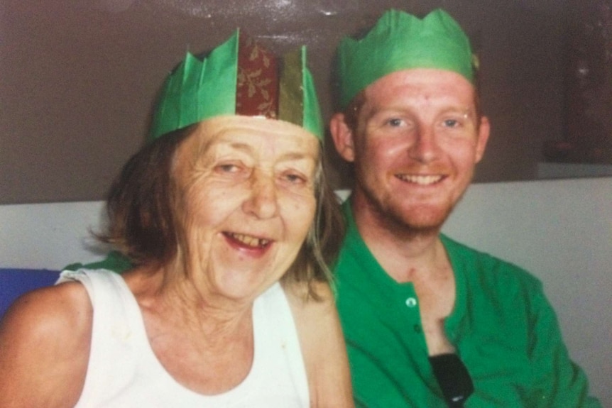 Mother and son sitting together with Christmas hats on.