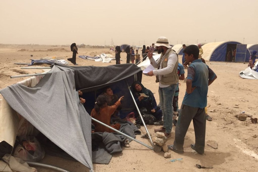 Aid workers at displacement camps speak to Iraqis sheltering in a tent